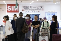 A group of Chinese tourists arrives at Haneda Airport in Tokyo in August after China lifted a ban on group tours to a slew of countries, including Japan. | Bloomberg