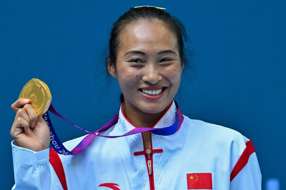 Zheng Qinwen poses on the podium after winning the women's final at the Asian Games in Hangzhou, China, on Friday.
