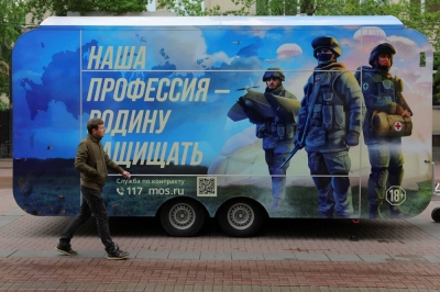 A pedestrian walks past a mobile recruitment point located to promote service in the Russian army and invite volunteers to sign a contract with the Defense Ministry, in a street in Moscow on May 3. The slogan reads: "Our profession is to defend fatherland."