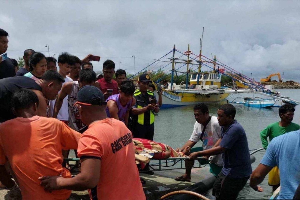 Philippine Coast Guard personnel retrieve the body of a crew member of a Filipino fishing boat on Wednesday. Three fishermen are dead after their boat was "rammed" by a foreign commercial vessel in the South China Sea, the Philippine Coast Guard said on October 4.