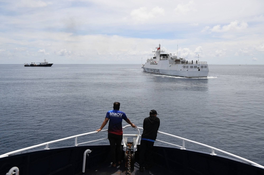 Philippine crew monitor a Chinese coast guard ship near the entrance of Chinese-controlled Scarborough Shoal in disputed waters in the South China Sea.