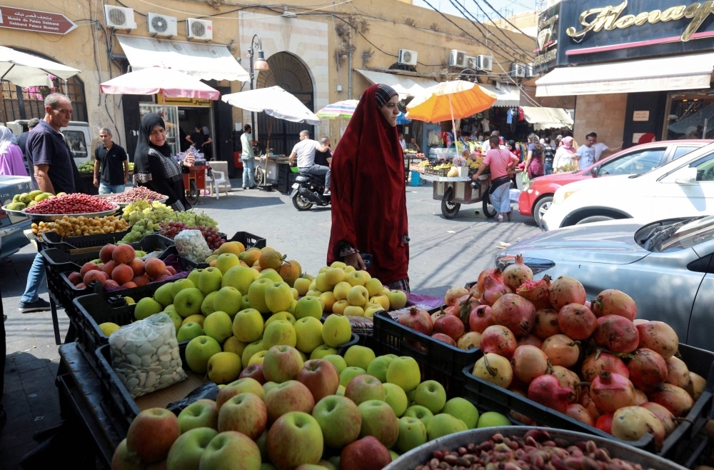 A woman walks past a market in the southern Lebanese city of Sidon. Lebanon is one of nine Arab nations using an algorithm-powered poverty assessment formula funded by the World Bank that ranks welfare applicants according to dozens of different data points.