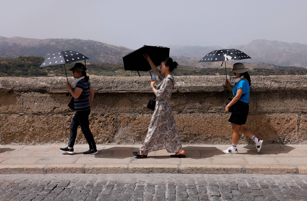 South Korean tourists shield themselves from the sun in Ronda, Spain, on Aug. 9. Much of the world sweltered through unseasonably warm weather in September, in a year expected to be the hottest in human history.