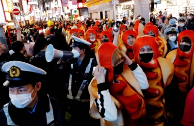 Police officers work to control a crowd gathering to celebrate Halloween in the Shibuya district of Tokyo on Oct. 31, 2022.