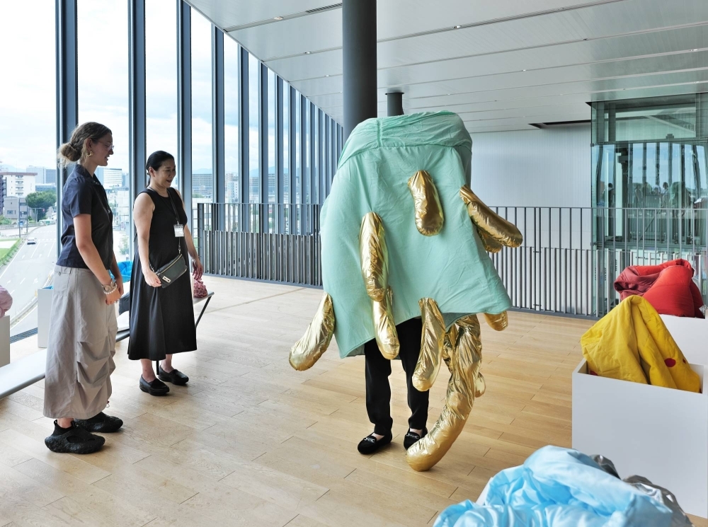 French artist Audrey Gambier (far left) observes a visitor to Go For Kogei’s “Material Imagination and Etiological Narrative: Material, Data, Fantasy” exhibition wearing one of her works at Toyama Prefectural Museum of Art and Design. 