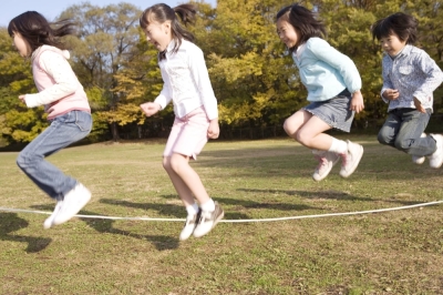 Children jump rope in a park. Young people with developmental coordination disorder (DCD) can have difficulties in jumping rope, throwing a ball or doing other common physical activities.