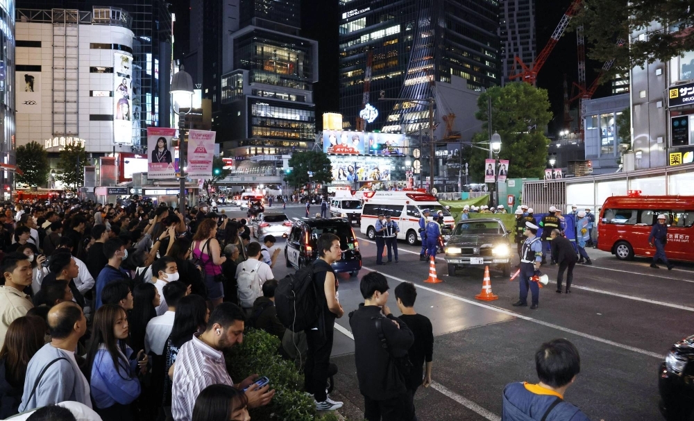 Pedestrians look on after a car plowed into a line of people in Tokyo's famous Shibuya scramble intersection Saturday evening.