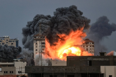 People standing on a rooftop watch as a ball of fire and smoke rises above a building in Gaza City, Gaza Strip, on Saturday during an Israeli airstrike. 