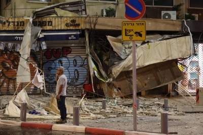 A man stands in front of a damaged shop in Tel Aviv after it was hit by a rocket fired by Palestinian militants from the Gaza Strip on Saturday. 
