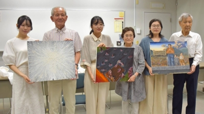 Students from Kyushu Sangyo University hold their paintings alongside three atomic bomb survivors whom they spoke with in a bid to depict hibakusha experiences on canvas, in Fukuoka in July.