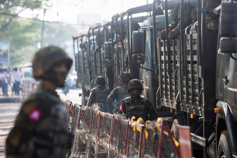 Soldiers stand near military vehicles as people protest against the military coup in Yangon in 2021.