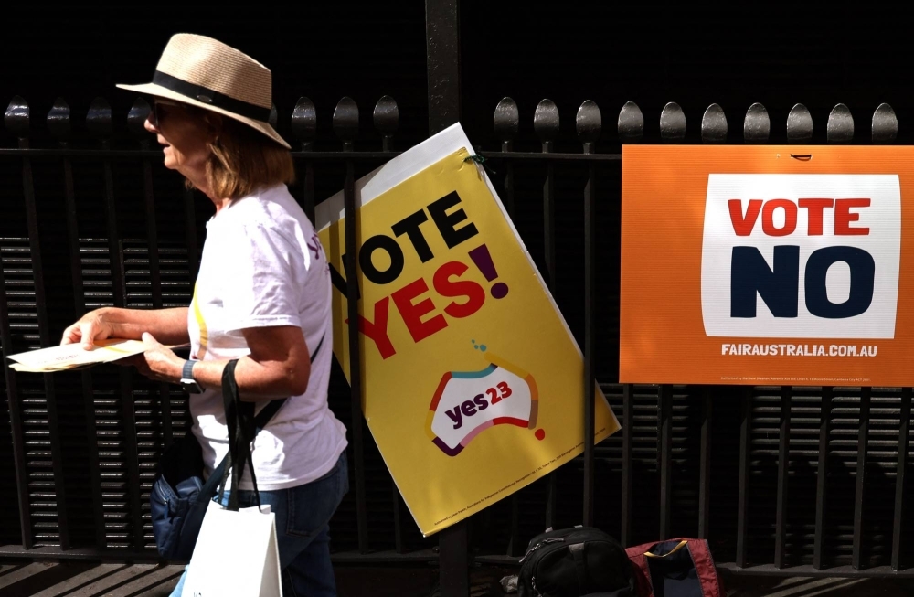 A woman hands out pamphlets outside a voting center in central Sydney on Oct. 3. A coming referendum will decide whether to recognize Indigenous Australians in the Constitution.