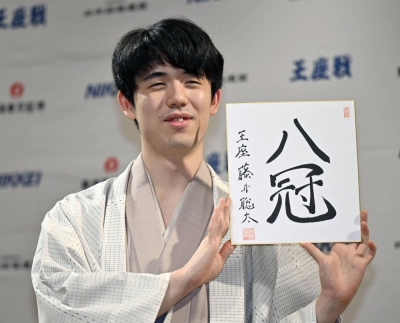 Shogi player Sota Fujii holds a card that says "eight titles," in the city of Kyoto on Wednesday.