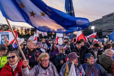 People wave Polish and EU flags as they gather outside a tv studio where the main candidates in the upcoming Polish elections are taking part in a debate in Warsaw on Monday.