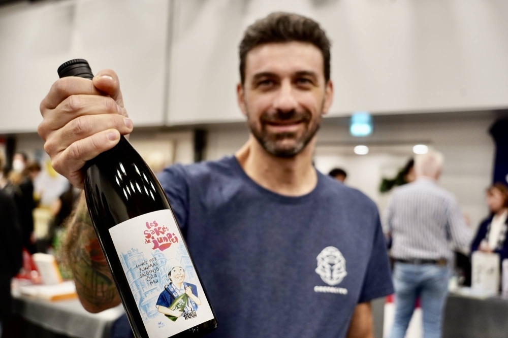 A representative of Chevalier Brewery presents a bottle of its sake adapted to French drinkers' tastes.