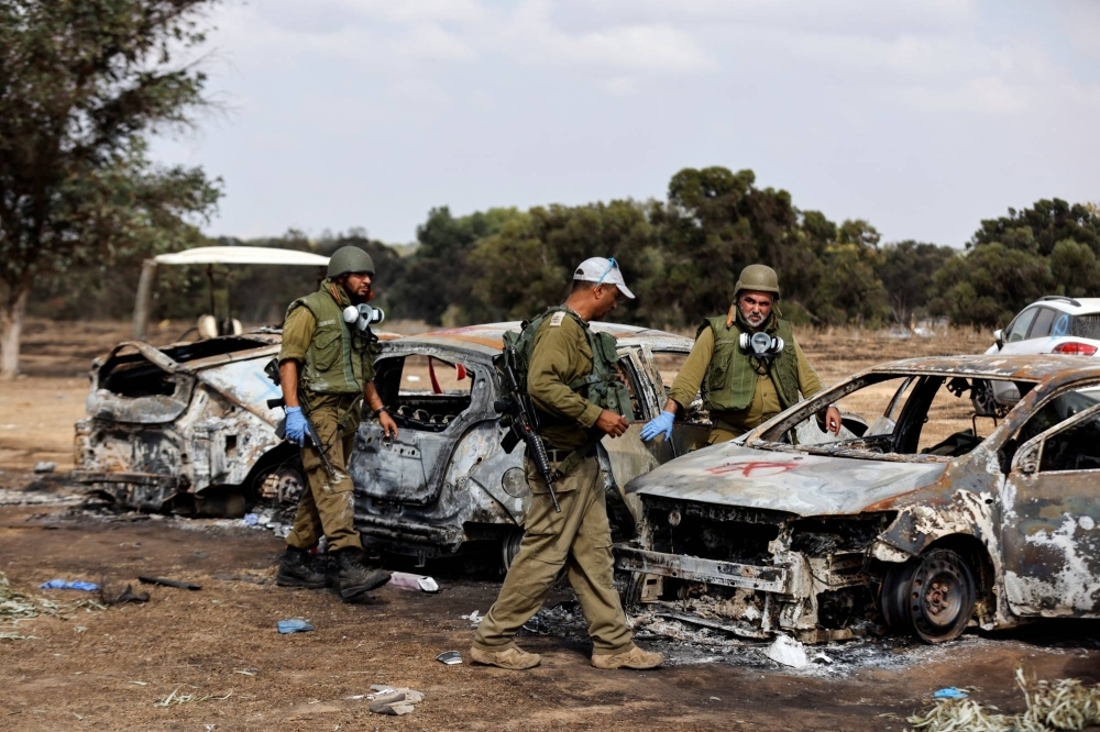 Israeli soldiers inspect the burned cars of festival-goers who were attacked and massacred by Hamas militants near the border with the Gaza Strip on Oct. 7