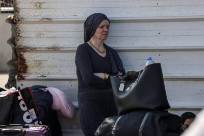 A Palestinian woman with a foreign passport waits at the Rafah gate hoping to cross into Egypt as Israel's attacks on the Gaza Strip continues on Saturday. 