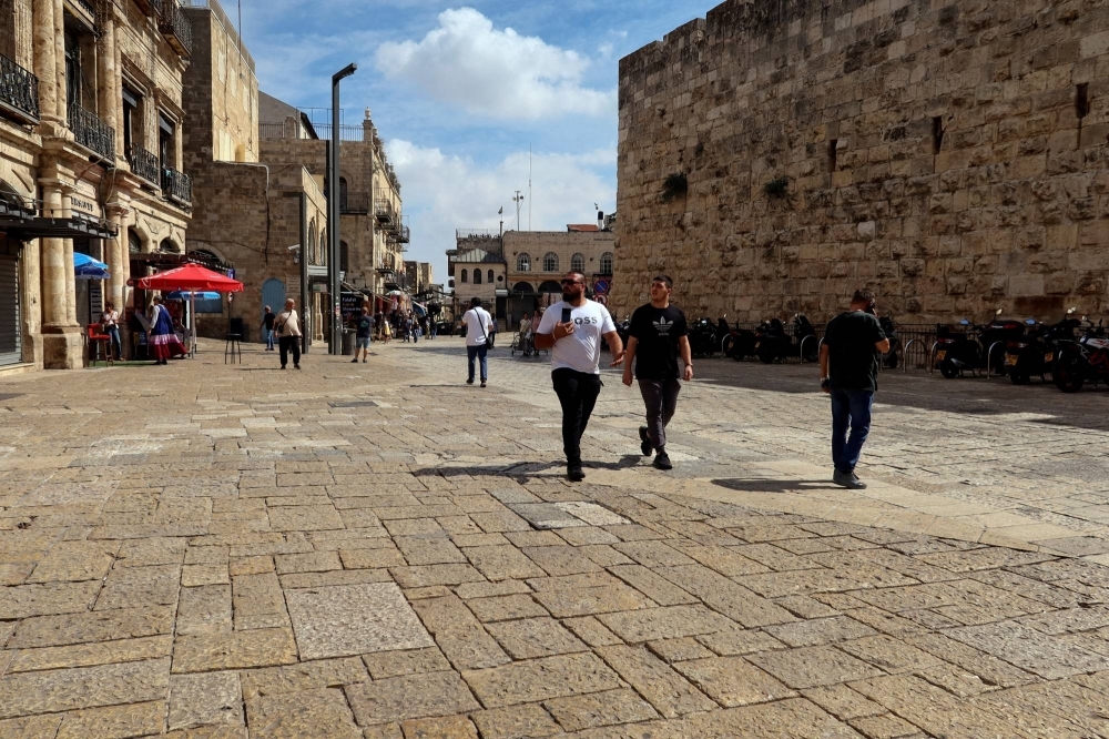 People walk into Jerusalem's Old City via Jaffa Gate, as the conflict wreaks havoc across the tourism sector.
