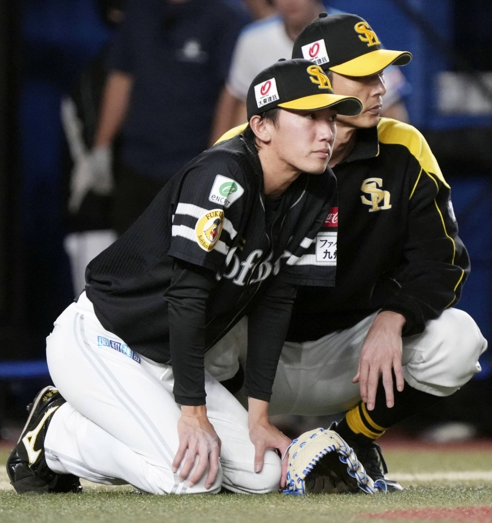 Hawks reliever Ryosuke Otsu (left) is comforted on the mount by pitching coach Kazumi Saito after surrendering the game-winning run against the Marines in Game 3 of the first stage of the PL Climax Series in Chiba on Monday.