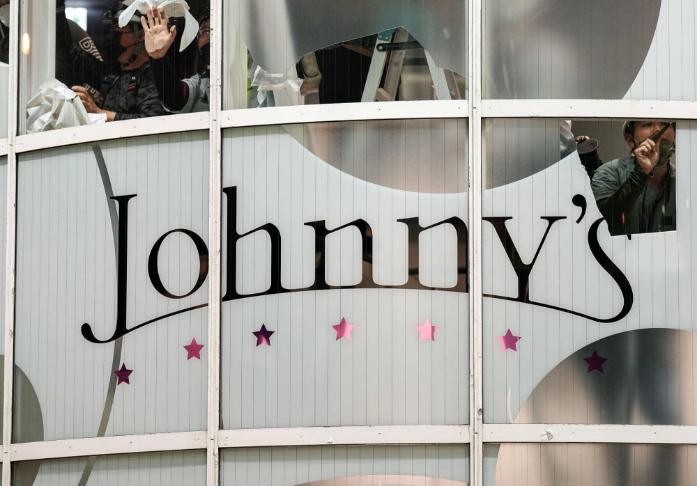 A sign at a Johnny & Associates store in the city of Osaka is peeled off late Monday after the shop closed.