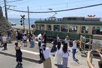 Tourists take pictures of an Enoshima Electric Railway train in Kamakura, Kanagawa Prefecture, in July. | Kyodo
