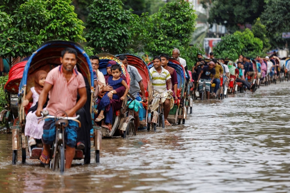 Commuters ride on rickshaws on a flooded road after heavy rains in Dhaka in September.