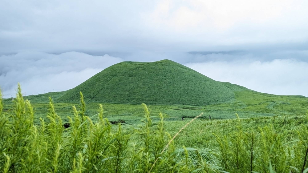 Aso's "sōgen" grasslands make up one of Japan's most unique landscapes, highlighted by sites like this "komezuka," a dormant, semi-collapsed volcano cone now overgrown with verdant grass.