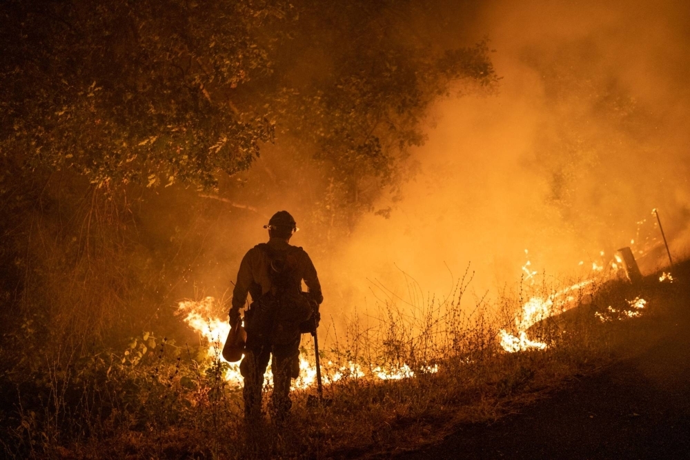 A firefighter holds a drip torch along Michigan Bluff Road during the Mosquito Fire near Foresthill, California. 