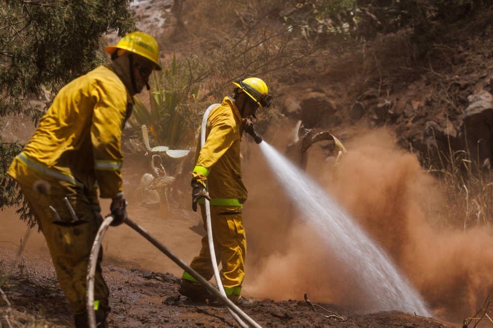 Maui County firefighters fight flare-up fires in a canyon in Kula on Maui island, Hawaii