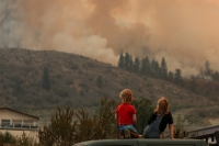Locals gather to watch firefighting efforts amid heavy smoke from the Eagle Bluff wildfire, after it crossed the Canada-U.S. border from the state of Washington and prompted evacuation orders, in Osoyoos, British Columbia, Canada | REUTERS