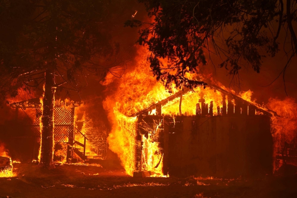 A house is fully engulfed by flames at the Dixie Fire, a wildfire near the town of Greenville, California