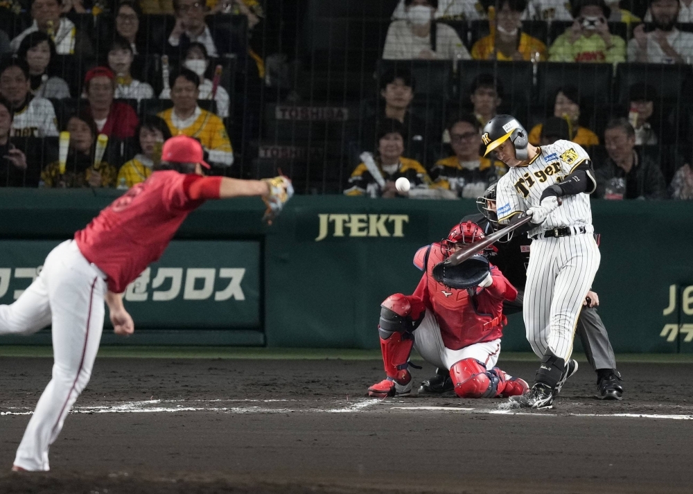 Catcher Seishiro Sakamoto hits the game-winning RBI single in the sixth inning on Friday at Koshien Stadium. 