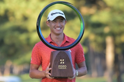 Collin Morikawa receives the winner's trophy after the final round of the Zozo Championship in Inzai, Chiba Prefecture, on Sunday.