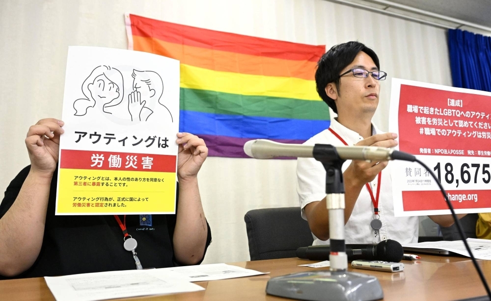 A man (left) who had been deemed eligible for compensation from his employer by a Tokyo labor office after his boss revealed he was gay without his consent attends a news conference at the health ministry in July.