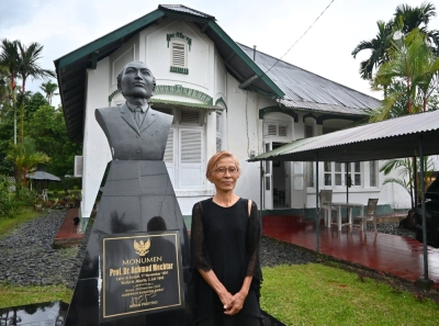 Siti Chairani Proehoeman stands in front of the house and statue of her mother's uncle Achmad Mochtar in the village of Ganggo Hilia in Indonesia's West Sumatra Province on June 9.