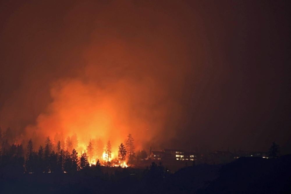 The McDougall Creek wildfire burns next to houses in the Okanagan community of West Kelowna, British Columbia, on Aug. 19.