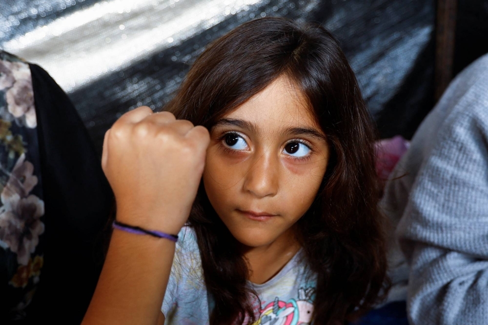 A daughter of Palestinian man Ali Daba shows her bracelet at their shelter in Khan Younis in the southern Gaza Strip, on Tuesday