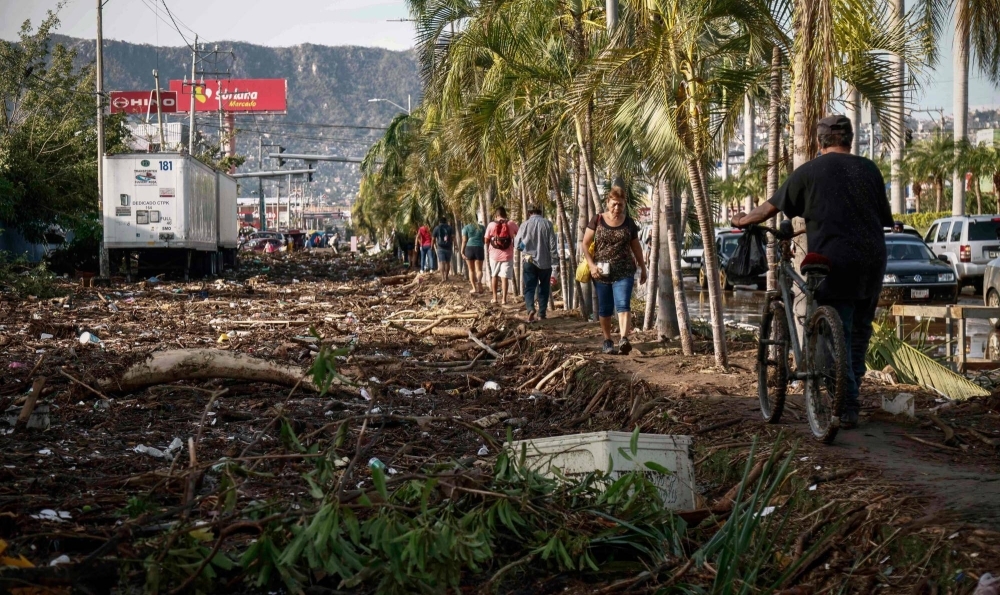People walk next to debris left after the passage of Hurricane Otis in Acapulco, Guerrero State, Mexico, on Thursday.