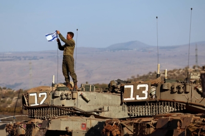 A soldier installs an Israeli flag on a tank during a military drill near Israel's border with Lebanon in northern Israel, on Thursday