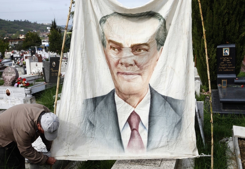 An Albanian communist hangs a banner with Enver Hoxha's image in a public cemetery in Tirana in April 2012 to mark the anniversary of the hard-line Stalinist dictator's death. 