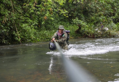 Thon Soukhon, who has been a ranger in Virachey since the forest became one of Cambodia’s first national parks in 1993, holds a rope as he crosses a rain-swollen river within the protected area.