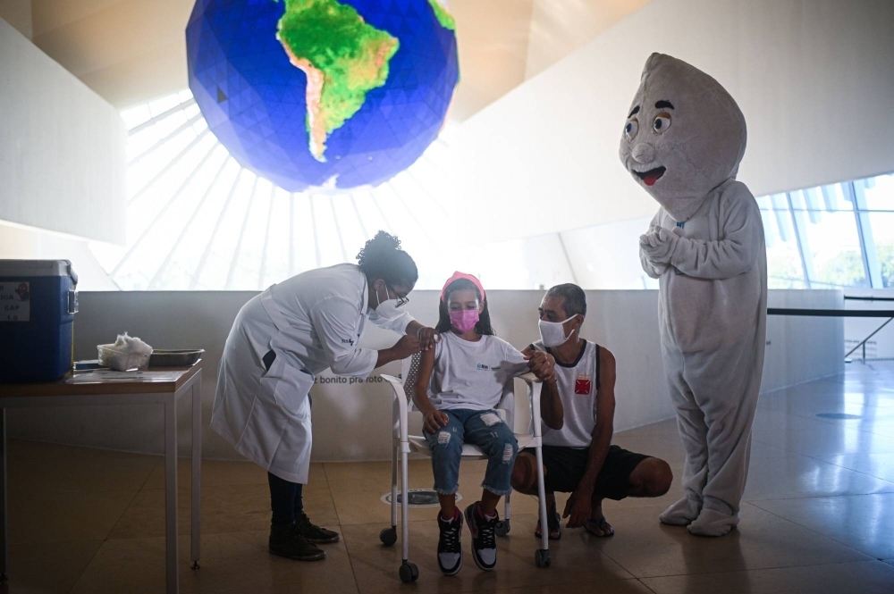 A health care worker administers the COVID-19 vaccine to a child in Rio de Janeiro in January 2022. 