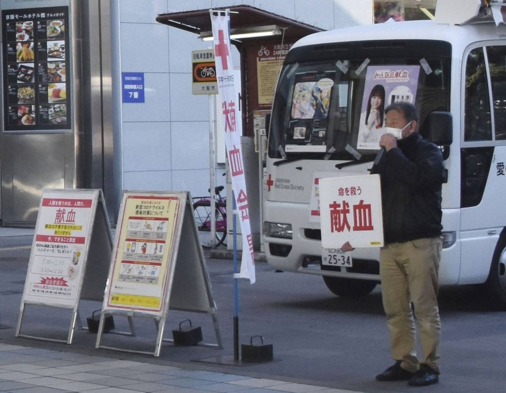 A Japanese Red Cross Society worker calls for blood donations in Osaka in January 2021.
