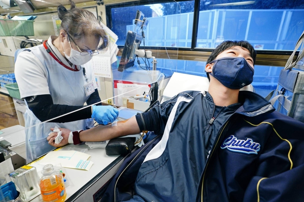 A member of a university baseball team participates in a group blood donation campaign in Aichi Prefecture in January 2022.