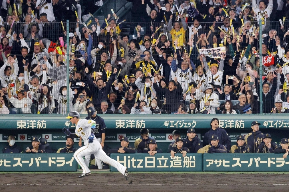 Tigers outfielder Koji Chikamoto races home to score the winning run in Hanshin's Game 4 win on Wednesday at Koshien Stadium. 