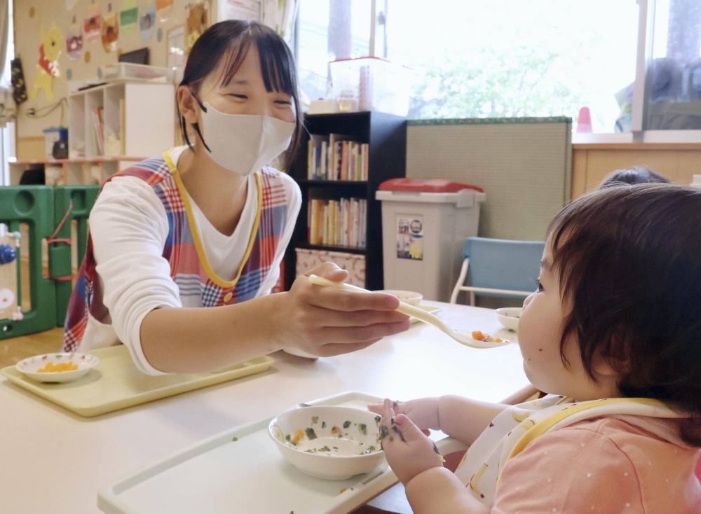 A day care worker feeds a child during a class at a nursery in Aira, Kagoshima Prefecture, in September. A 6-month-old infant died after being fed uncooked grated apple at a different facility in the city in April.
