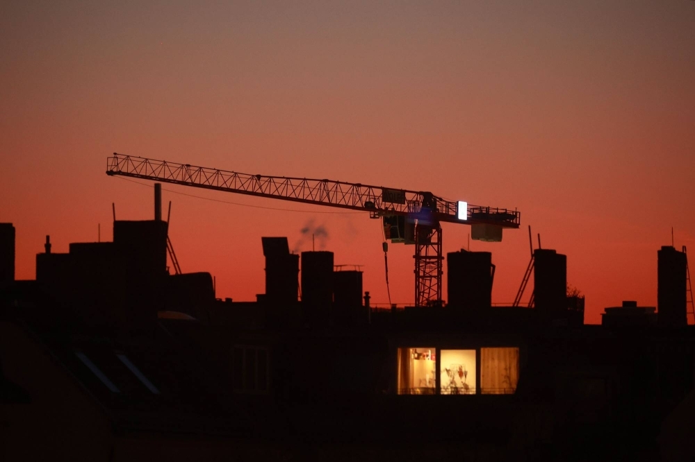 A construction crane beyond an apartment building at dusk in the Prenzlauer Berg district in Berlin, in February.