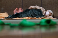 A woman sleeps in an evacuation center for residents affected by flooding following Typhoon Hagibis in Nagano in October 2019. | Reuters 