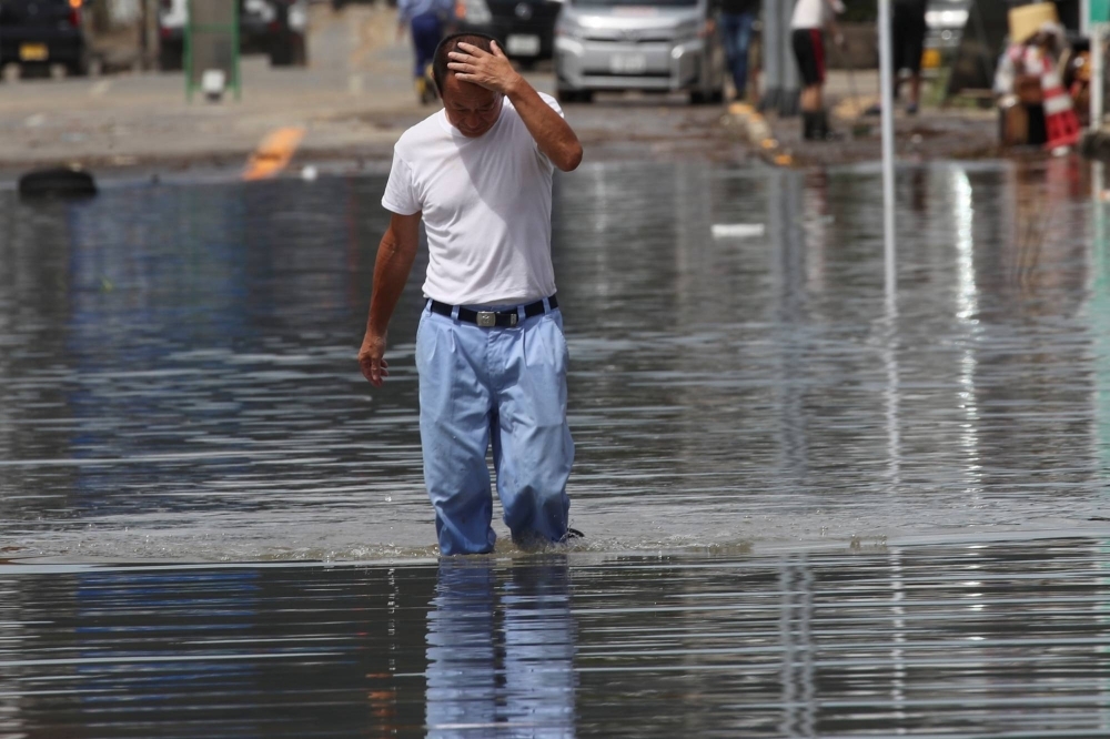A man wades through a flooded street in Takeo, Saga Prefecture, in August 2021. 