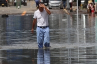 A man wades through a flooded street in Takeo, Saga Prefecture, in August 2021.  | Reuters 